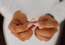 Zašto izabrati vereničko prstenje sa laboratorijskim dijamantima? Mlada drži verenički prsten sa dijamantom u rukama s prelepim manikirom, pogled spreda — dan venčanja.