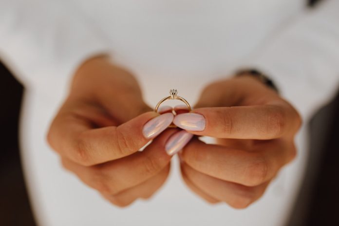 Engagement ring Mlada drži verenički prsten sa dijamantom u rukama s prelepim manikirom, pogled spreda — dan venčanja.